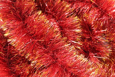 Photo of Shiny red tinsel as background, closeup view