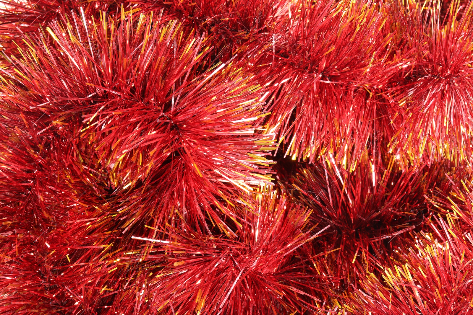 Photo of Shiny red tinsel as background, closeup view