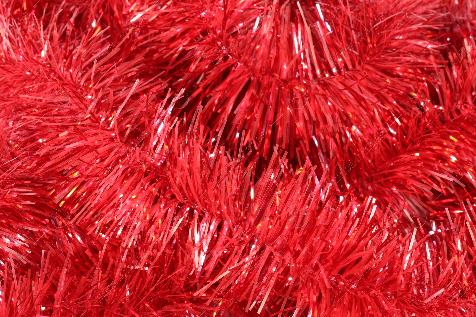 Photo of Shiny red tinsel as background, closeup view