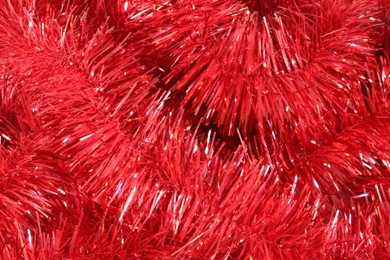 Photo of Shiny red tinsel as background, closeup view