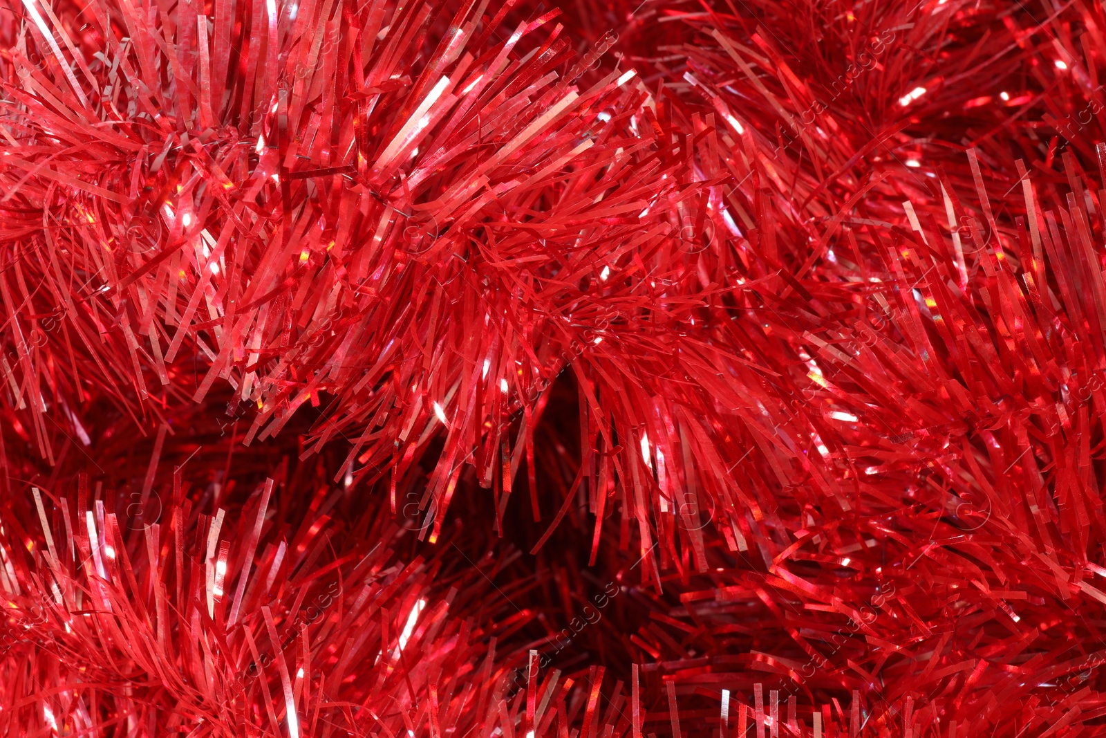 Photo of Shiny red tinsel as background, closeup view