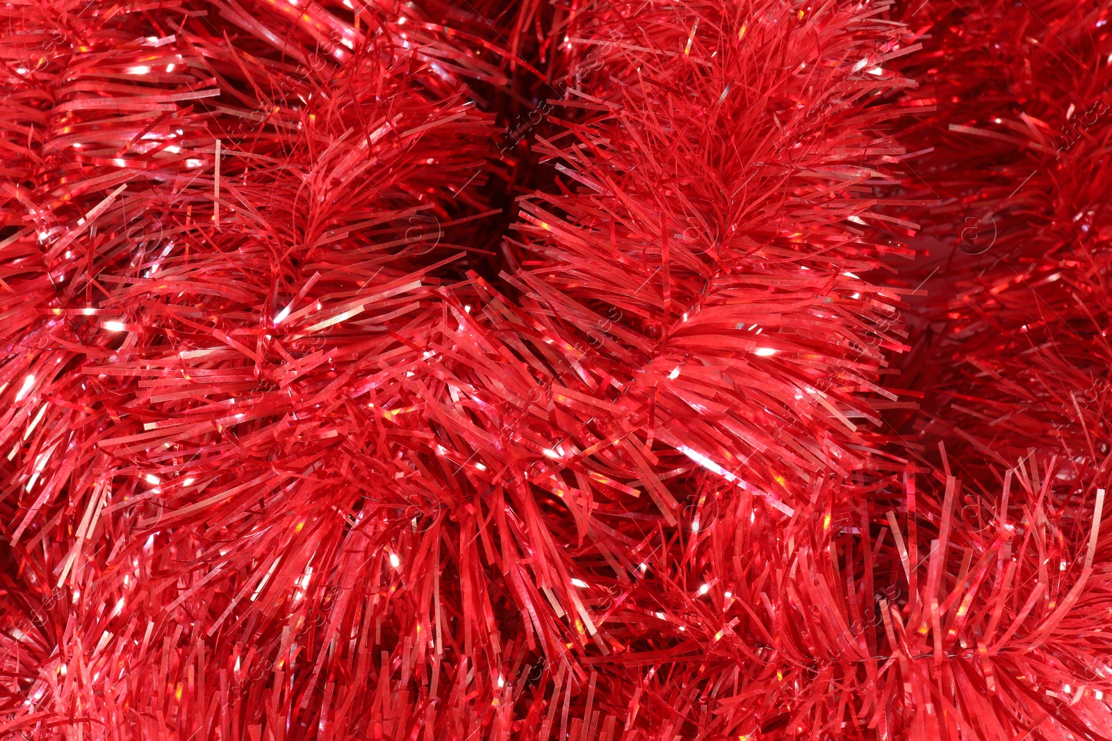 Photo of Shiny red tinsel as background, closeup view