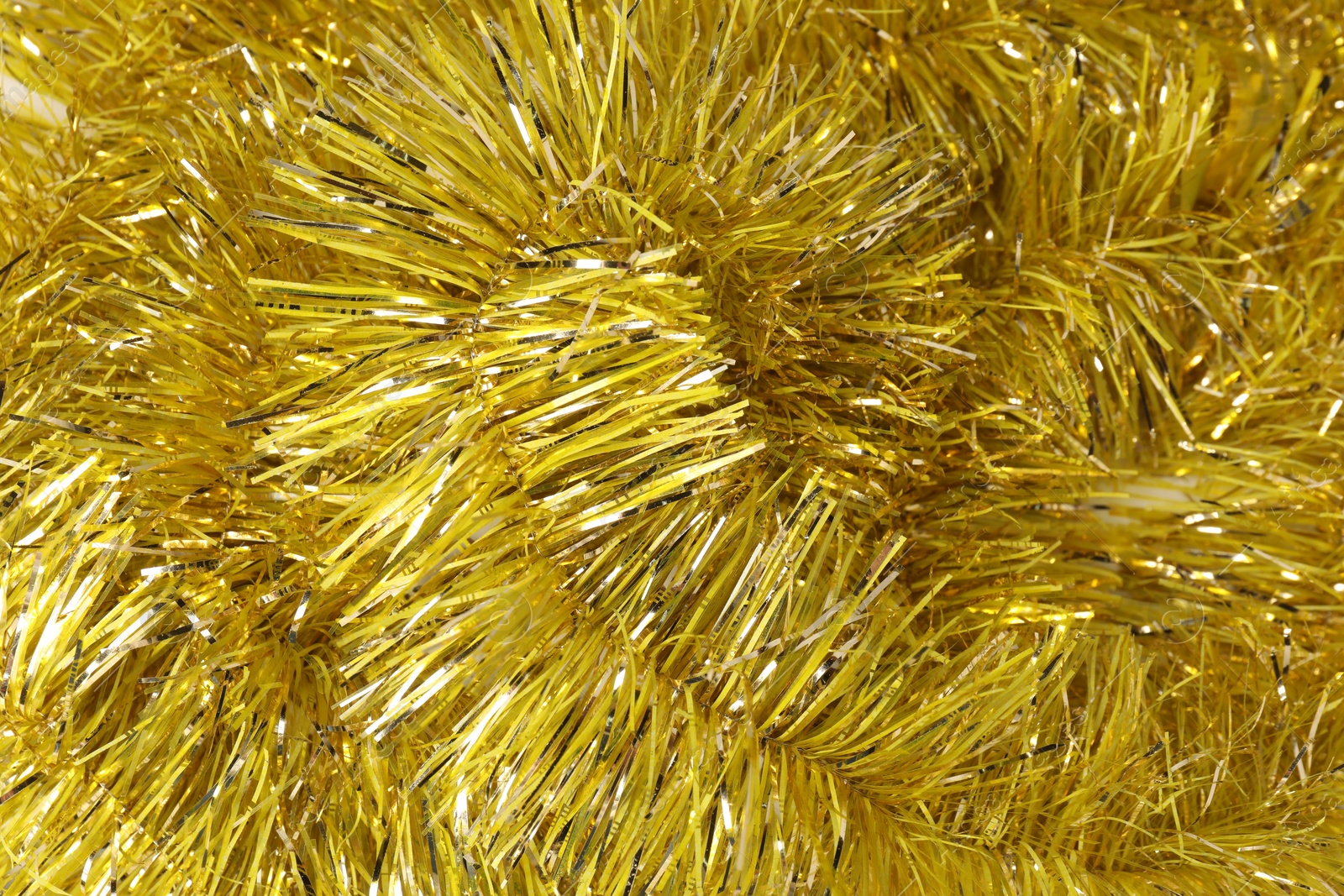 Photo of Shiny yellow tinsel as background, closeup view