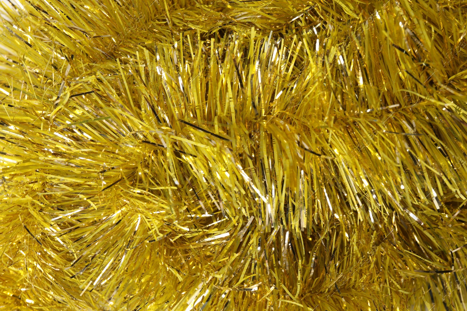 Photo of Shiny yellow tinsel as background, closeup view