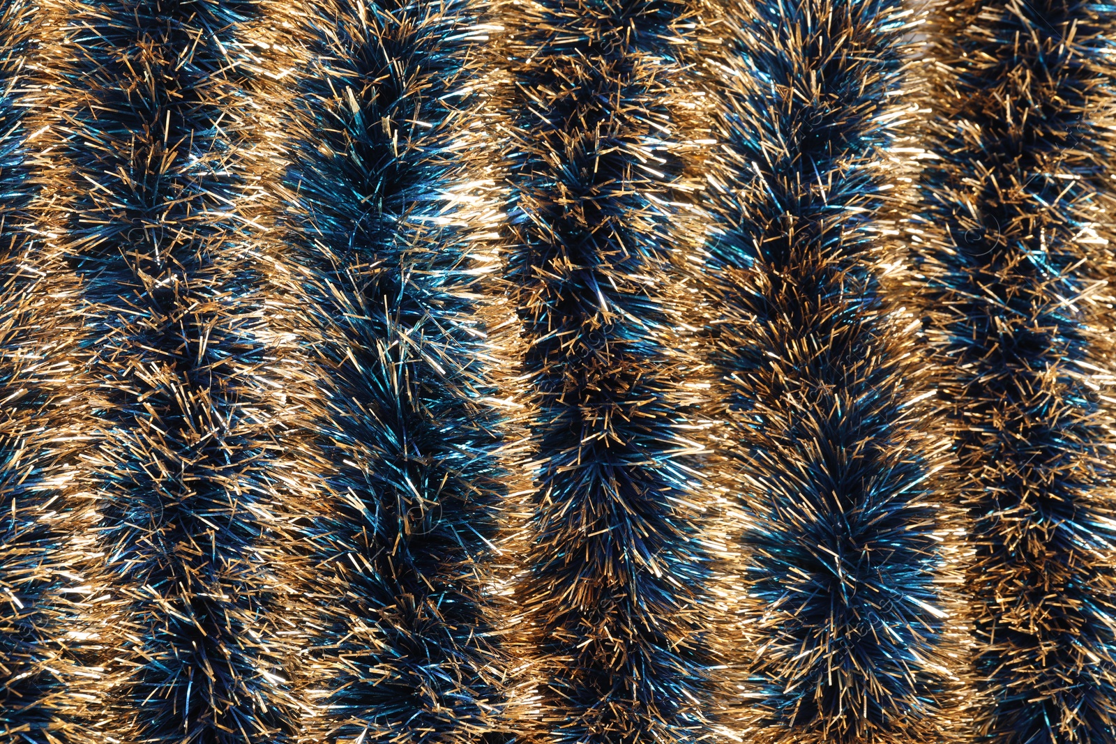 Photo of Beautiful shiny tinsel as background, closeup view