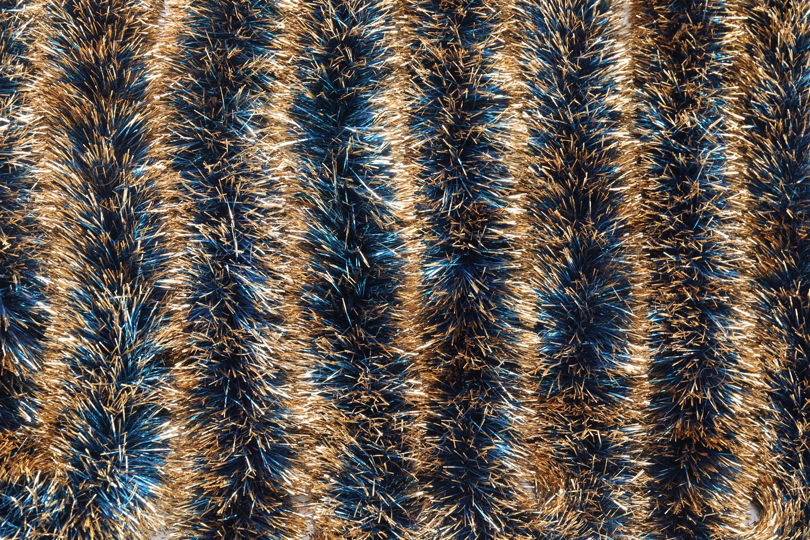 Photo of Beautiful shiny tinsel as background, closeup view