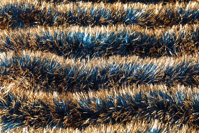 Photo of Beautiful shiny tinsel as background, closeup view