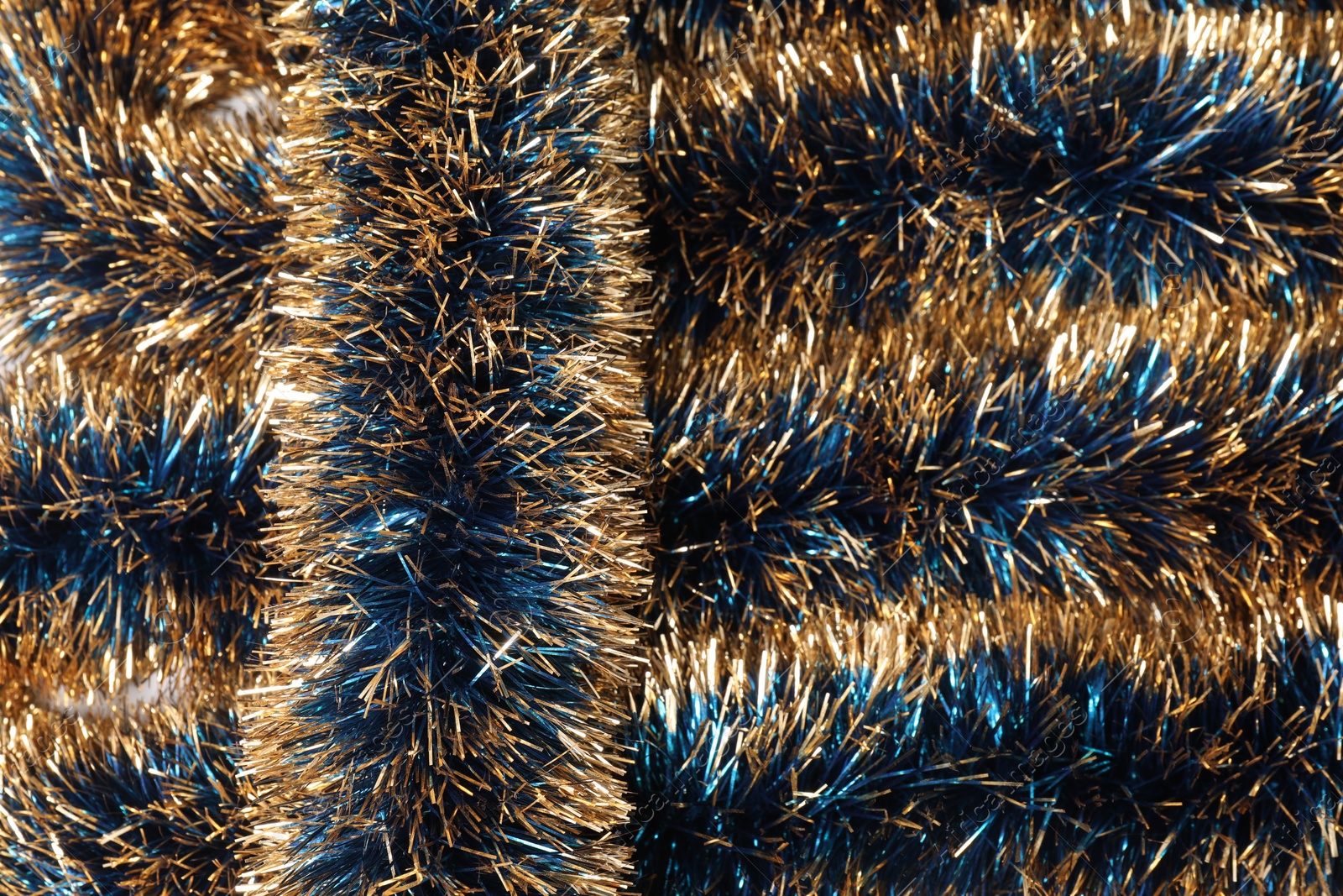 Photo of Beautiful shiny tinsel as background, closeup view