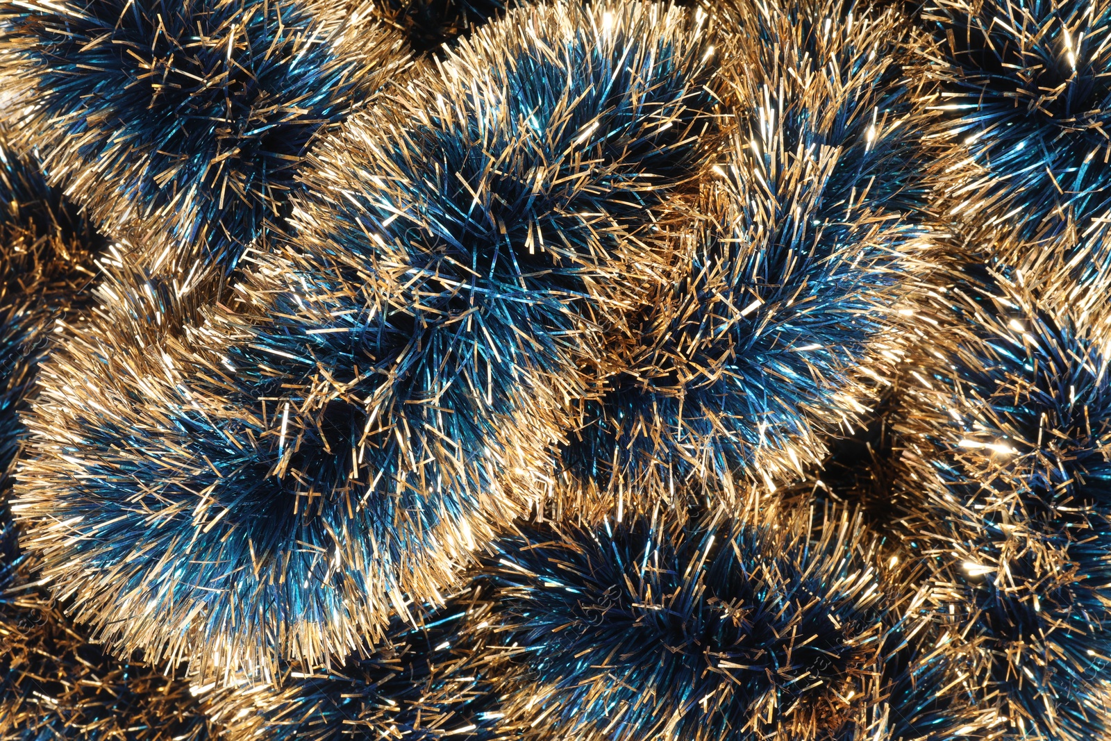 Photo of Beautiful shiny tinsel as background, closeup view