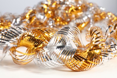 Photo of Beautiful shiny tinsel on white table, closeup