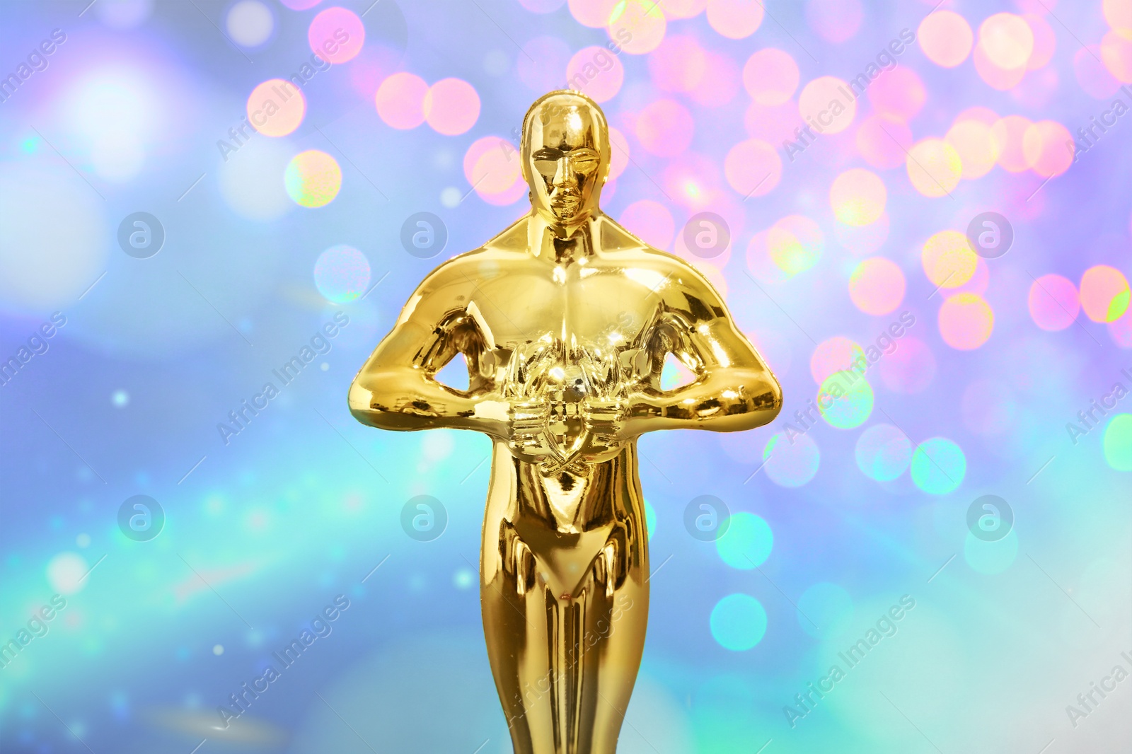 Image of Golden trophy in shape of human figure on colorful background with blurred lights