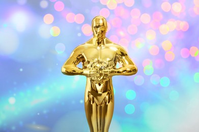 Image of Golden trophy in shape of human figure on colorful background with blurred lights