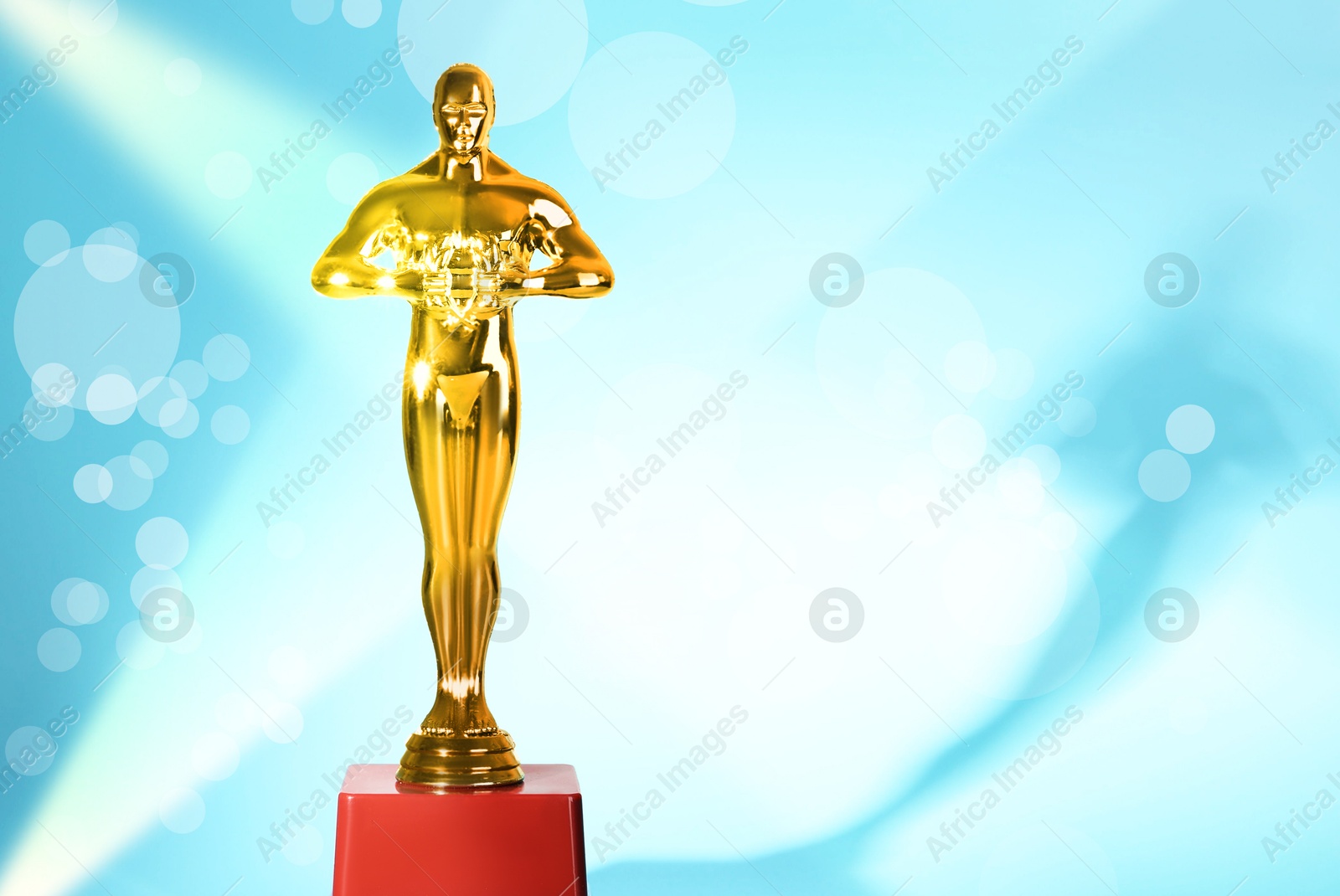 Image of Golden trophy in shape of human figure in light rays against light blue background