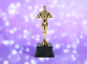 Image of Golden trophy in shape of human figure on violet shimmering background