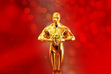 Image of Golden trophy in shape of human figure against red background with blurred lights