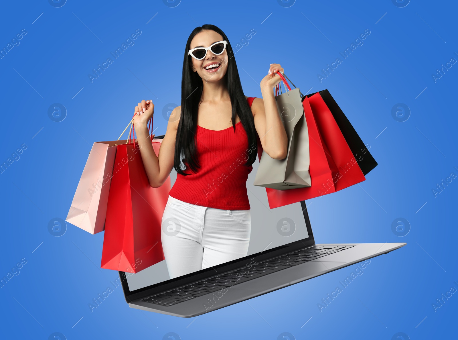 Image of Internet shopping. Happy woman with shopping bags coming out of laptop on blue background