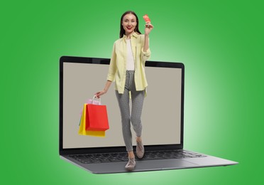 Internet shopping. Happy woman with credit card and shopping bags walking on laptop against green background