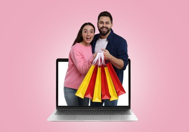 Internet shopping. Happy couple with shopping bags coming out of laptop on pink background