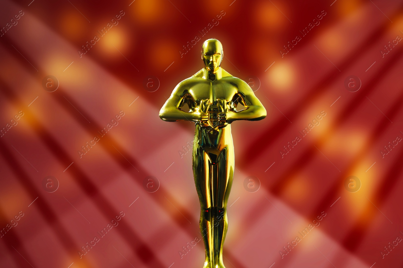 Image of Golden trophy in shape of human figure in light rays against red background