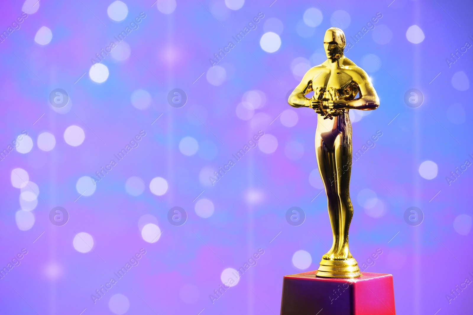 Image of Golden trophy in shape of human figure against blurred lights