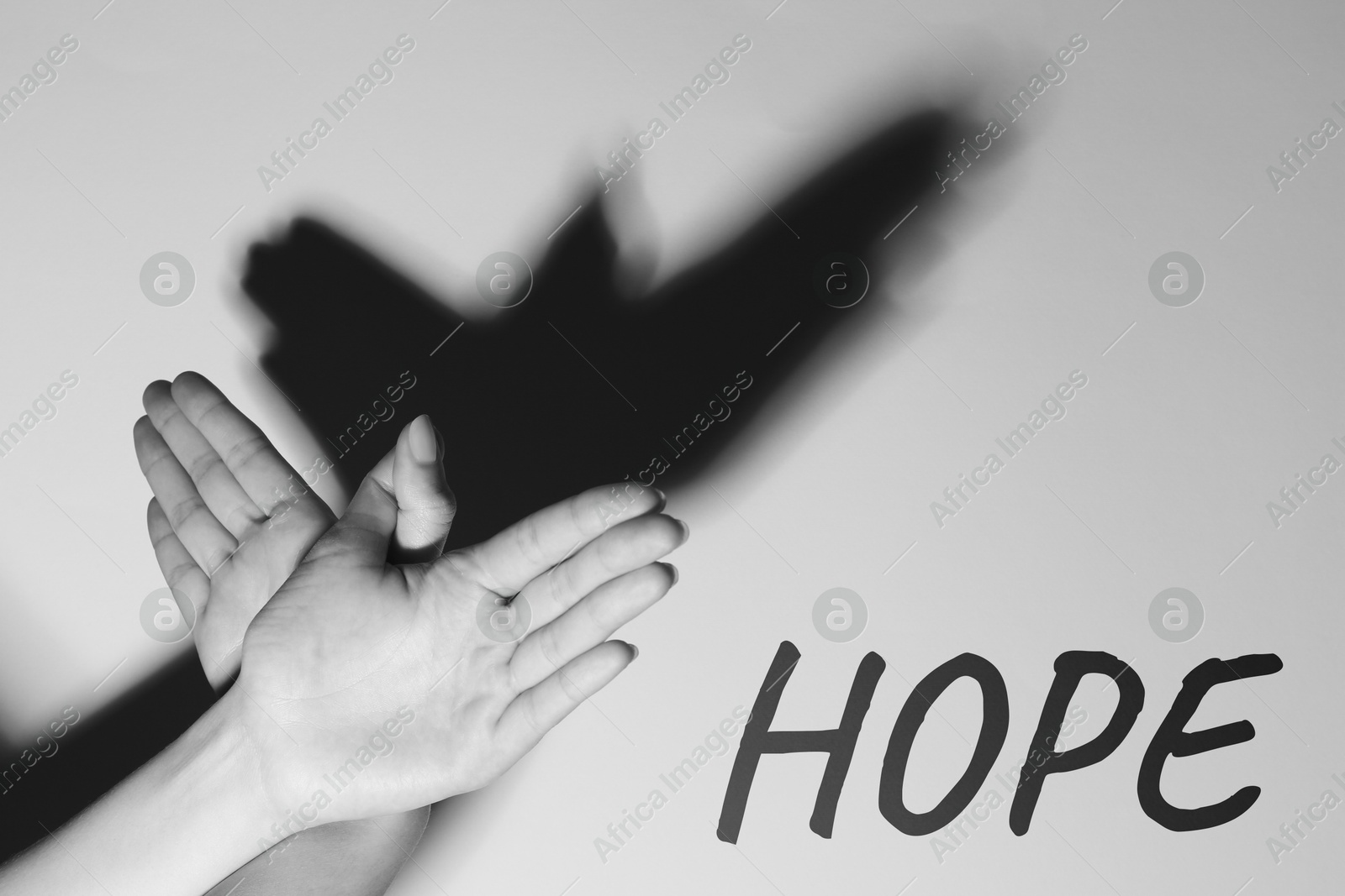 Image of Hope. Woman showing bird with hand shadows on light background, closeup