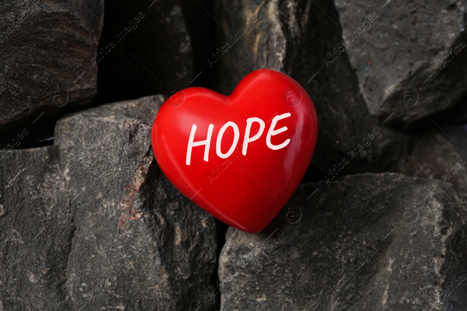 Image of Red decorative heart with word Hope on stones, top view