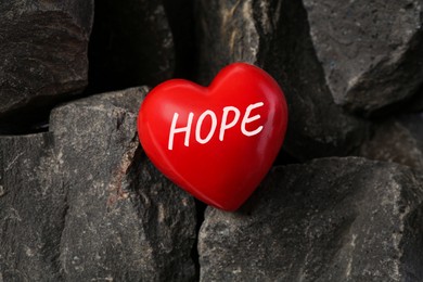 Image of Red decorative heart with word Hope on stones, top view