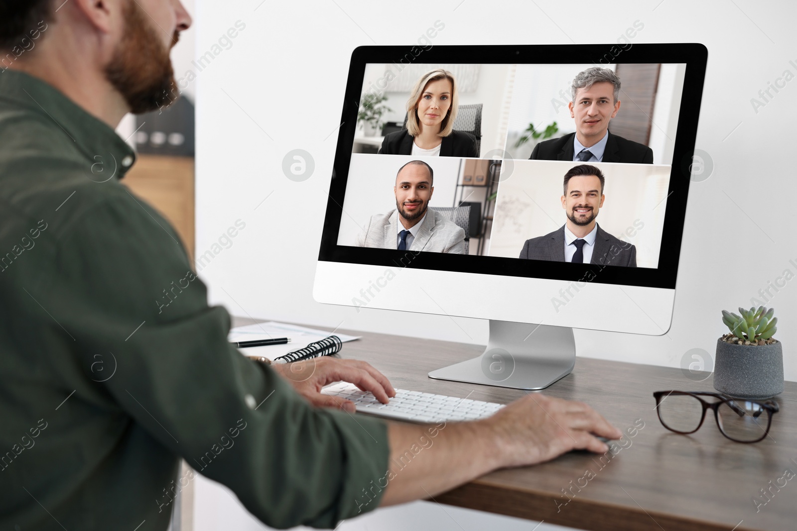 Image of Business meeting. Man using computer during online video chat at table, closeup