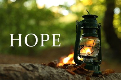 Image of Hope. Vintage kerosene lamp near bonfire in forest