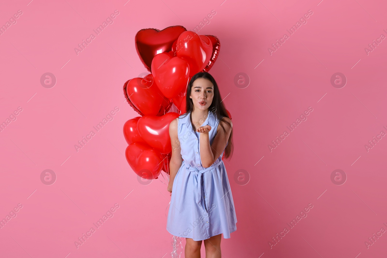 Photo of Beautiful young woman with heart shaped balloons on pink background. Valentine's day celebration