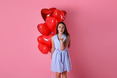 Beautiful young woman with heart shaped balloons on pink background. Valentine's day celebration