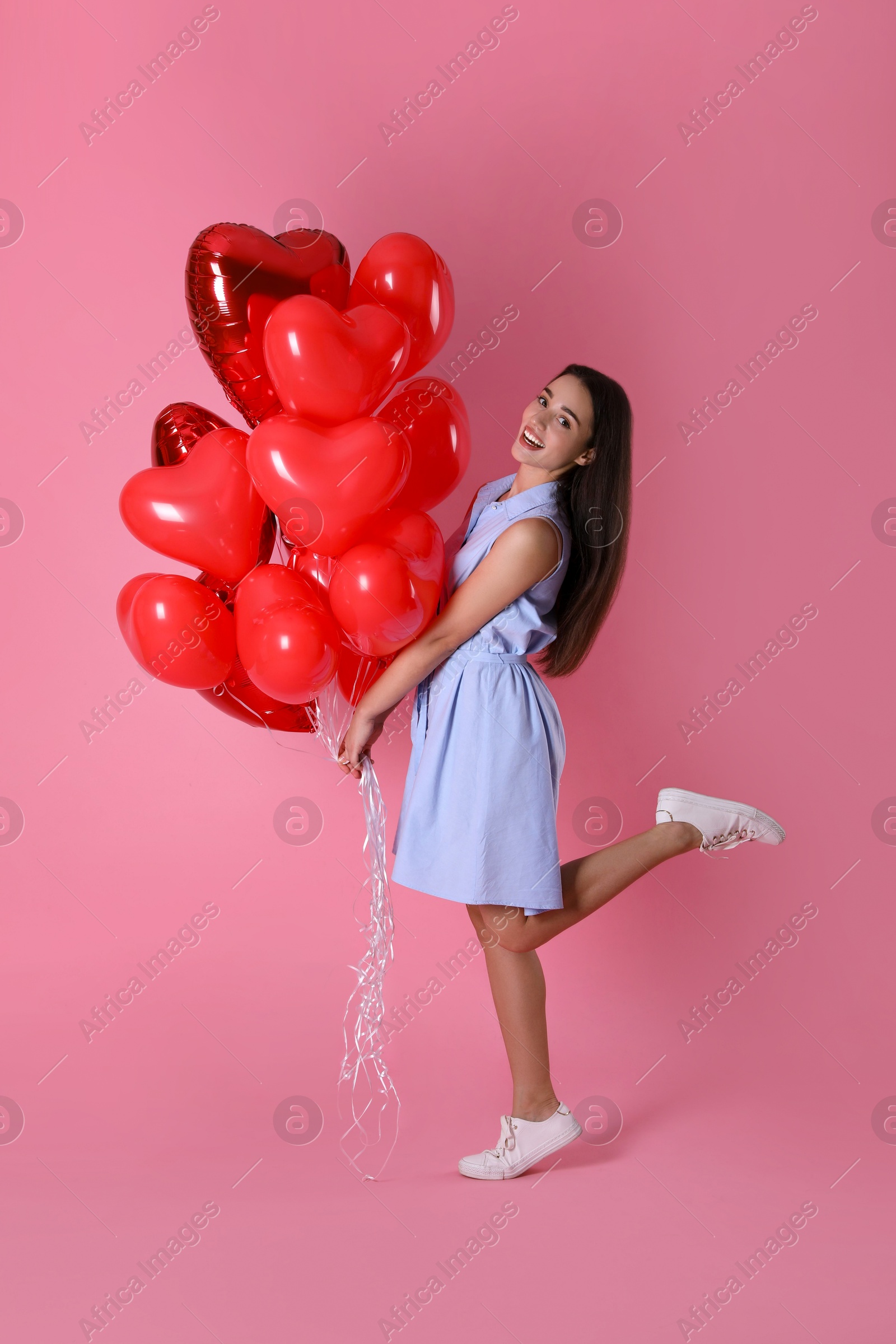 Photo of Beautiful young woman with heart shaped balloons on pink background. Valentine's day celebration