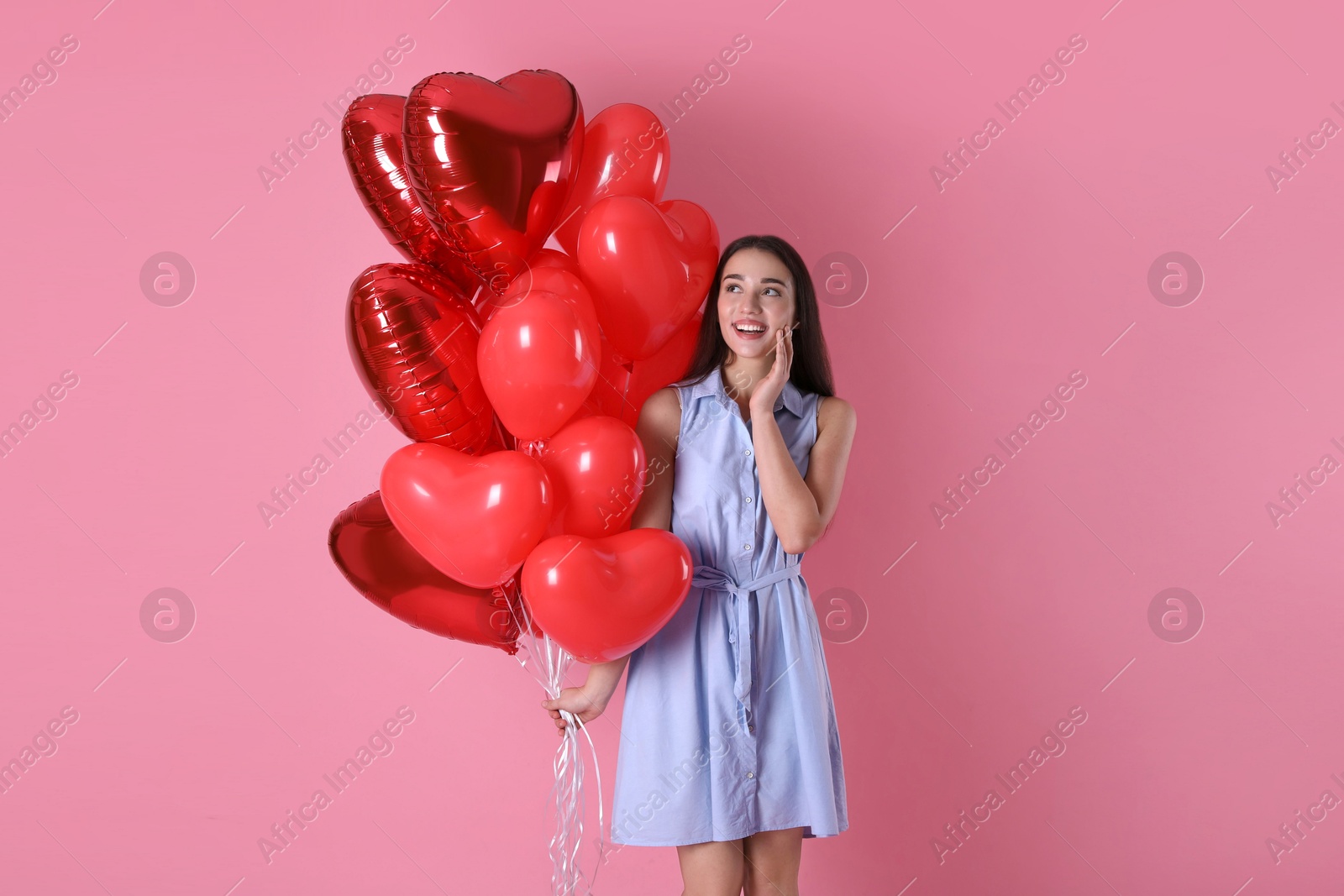 Photo of Beautiful young woman with heart shaped balloons on pink background. Valentine's day celebration