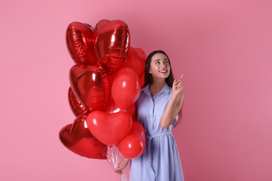 Photo of Beautiful young woman with heart shaped balloons on pink background. Valentine's day celebration