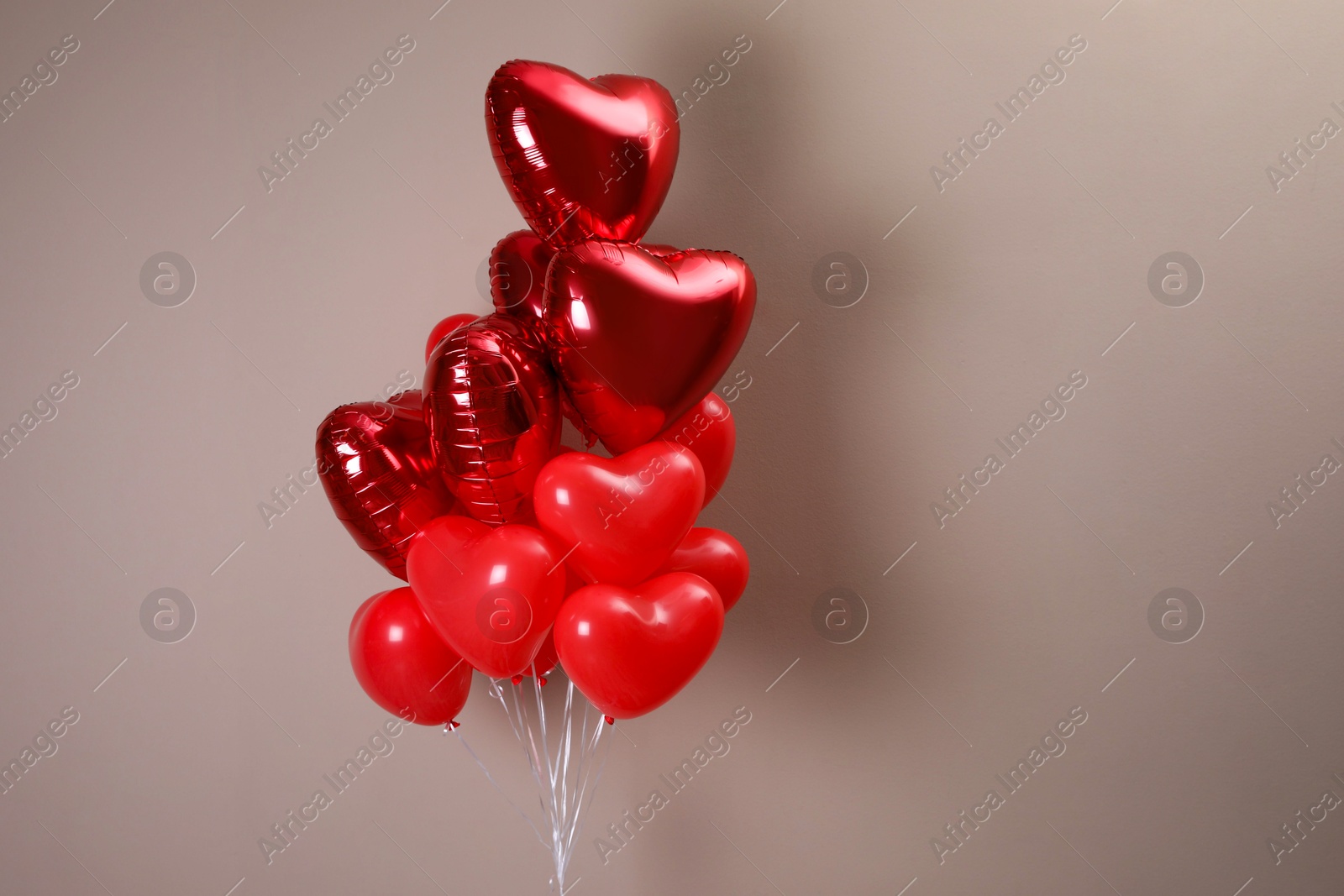 Photo of Bunch of heart shaped balloons on beige background. Valentine's day celebration