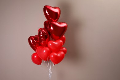 Photo of Bunch of heart shaped balloons on beige background. Valentine's day celebration