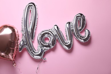 Photo of LOVE word and heart balloons on pink background, flat lay