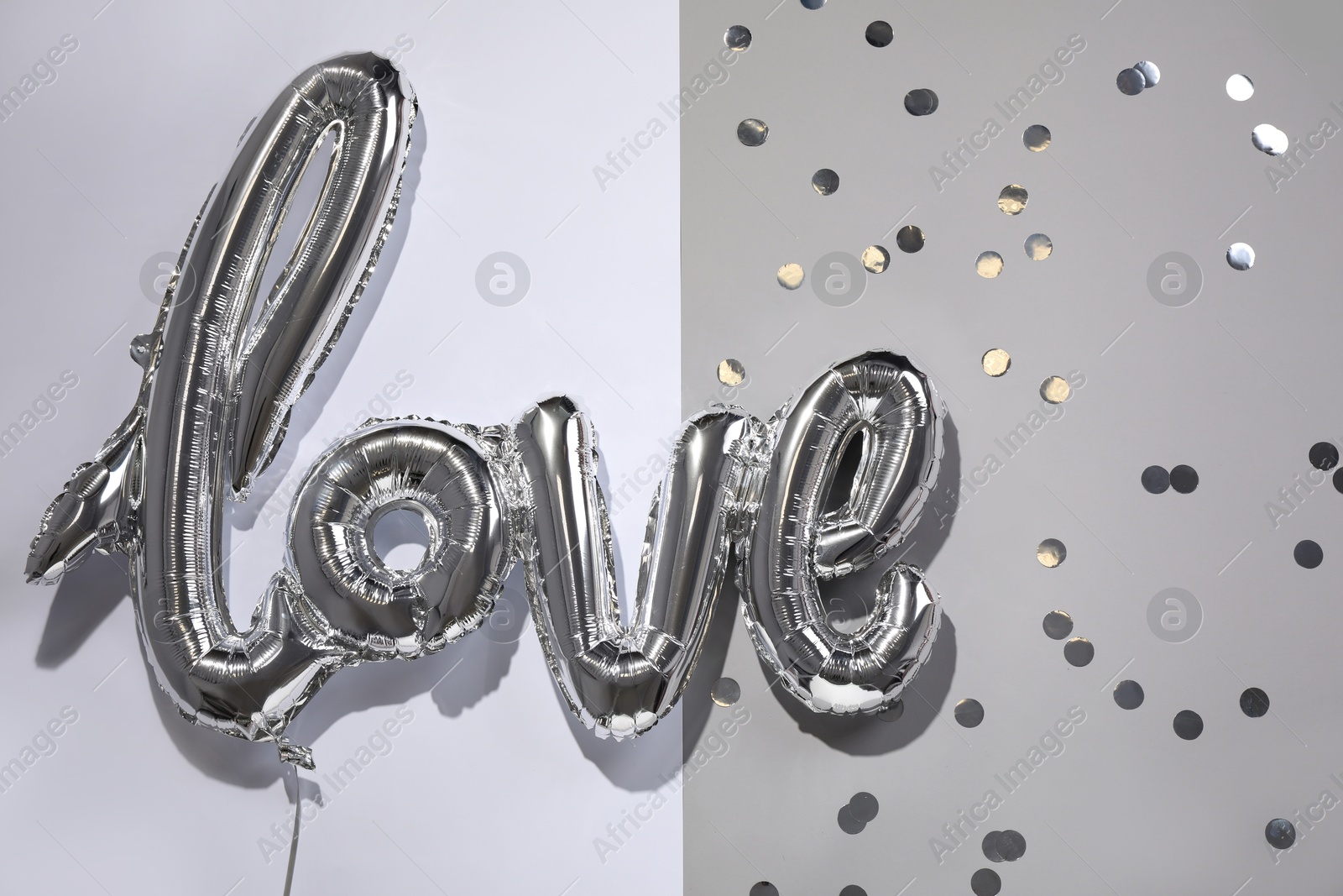 Photo of Foil balloon in shape of word LOVE on color background, top view