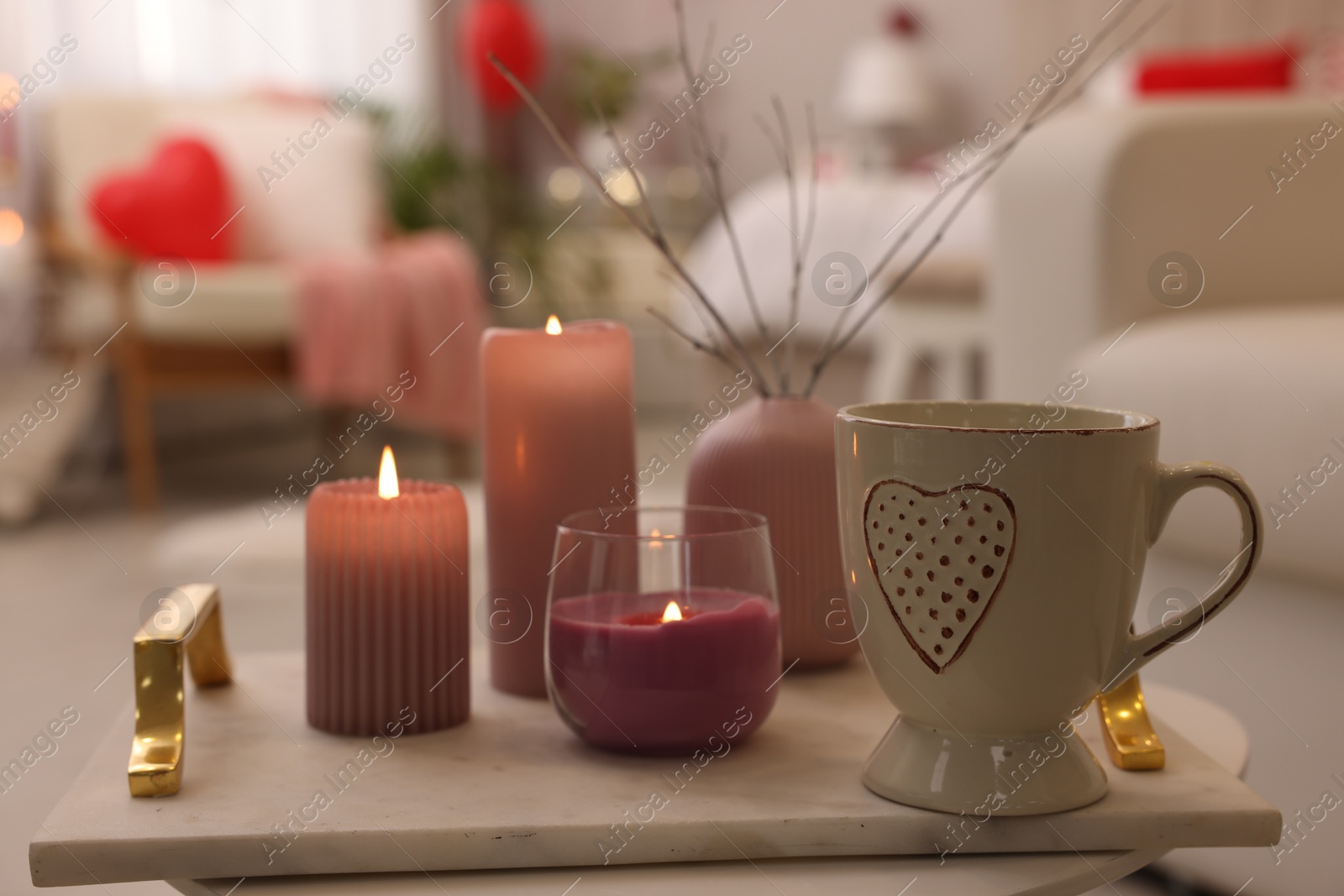 Photo of Burning candles and cup of hot drink on table in room