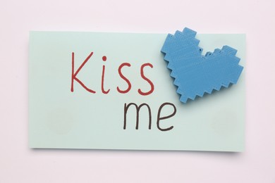 Photo of Card with phrase Kiss me and blue heart on white background, top view