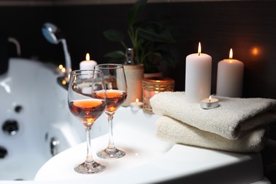 Photo of Bathtub with glasses of wine and candles indoors. Romantic atmosphere