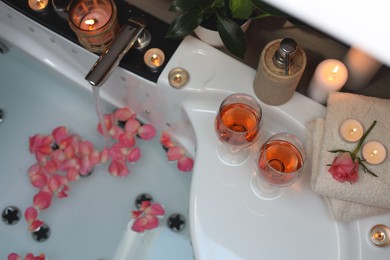 Photo of Bathtub with glasses of wine and candles indoors, above view. Romantic atmosphere