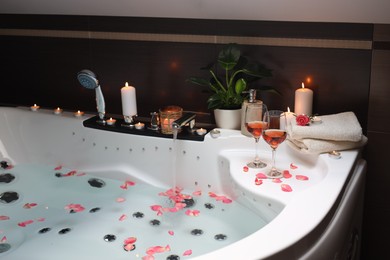 Photo of Bathtub with glasses of wine and candles indoors. Romantic atmosphere