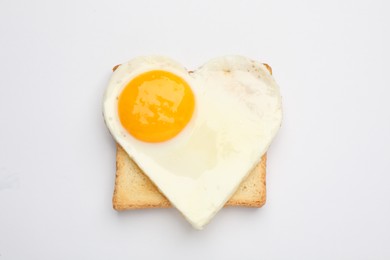 Photo of Tasty fried egg in shape of heart with toast isolated on white, top view