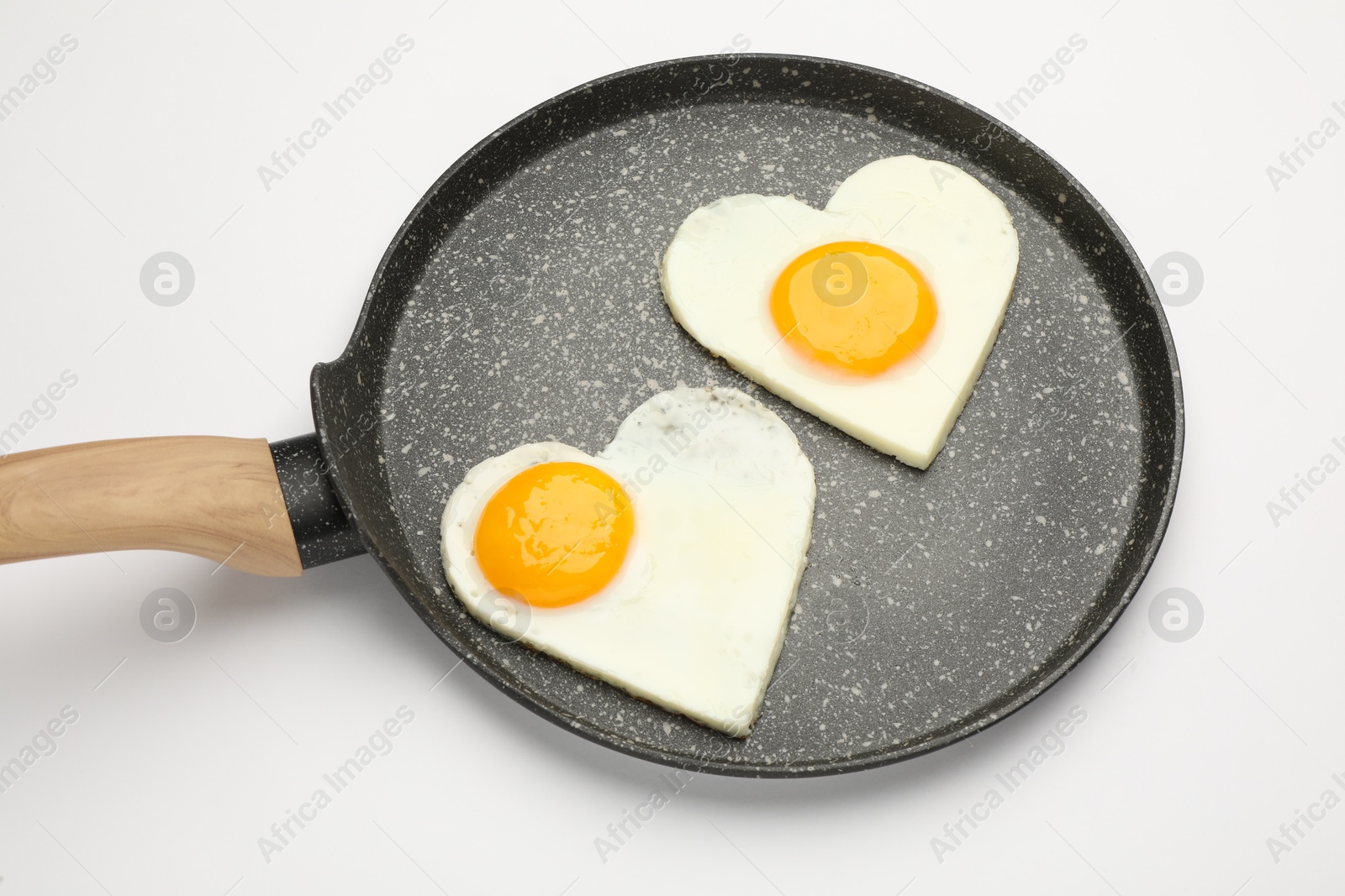 Photo of Heart shaped fried eggs in frying pan isolated on white