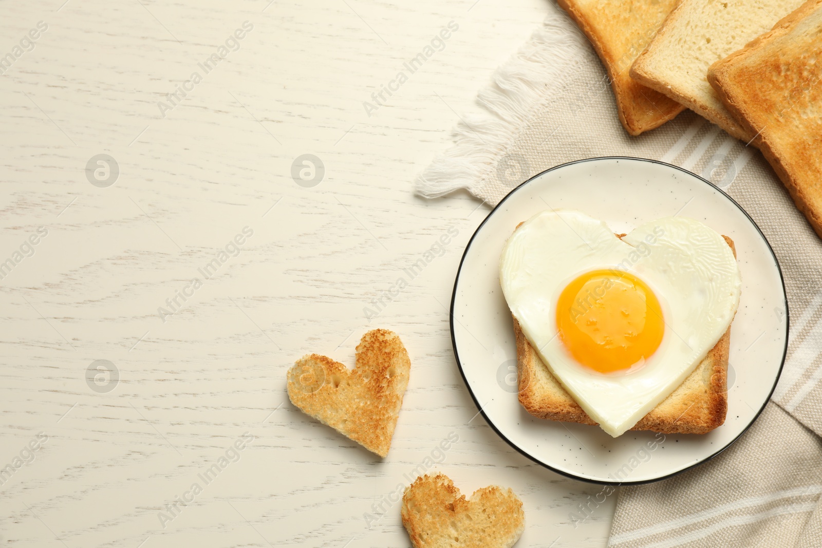 Photo of Heart shaped fried egg and toasts on white wooden table, flat lay. Space for text