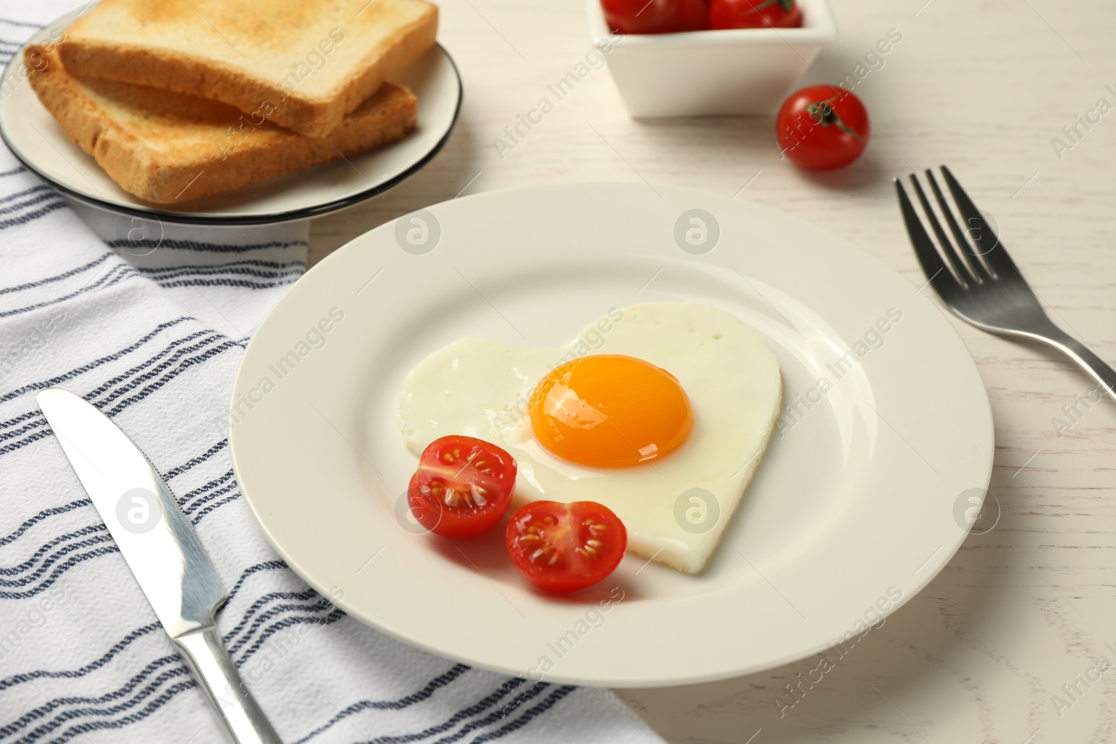 Photo of Heart shaped fried egg served on white wooden table