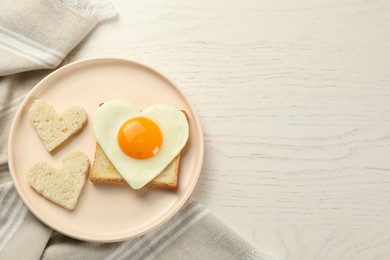 Photo of Plate with heart shaped fried egg and toasts on white wooden table, flat lay. Space for text