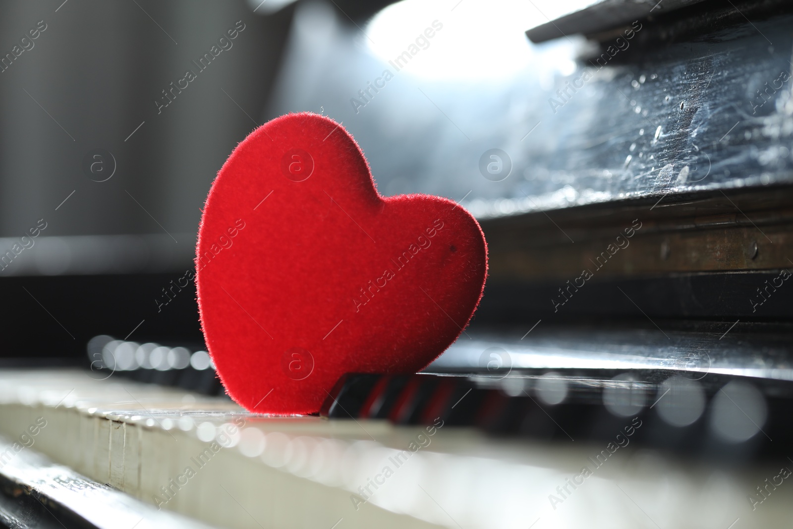 Photo of Small red decorative heart on piano keys, closeup. Space for text