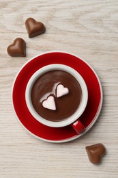 Photo of Cup of hot chocolate with heart shaped marshmallows and candies on white wooden table, flat lay